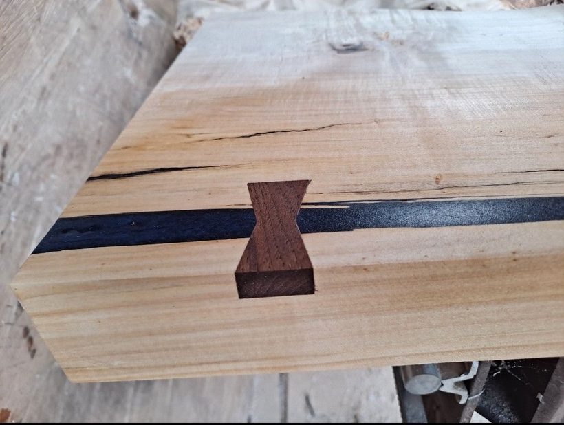 A close view of a walnut butterfly key inlaid across a check, sanded flush with the surface.