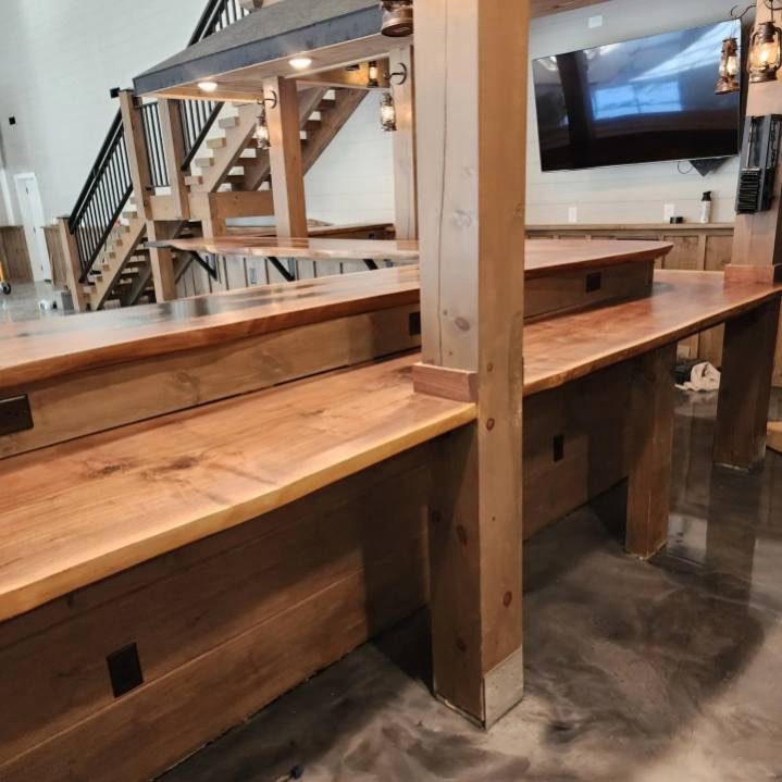 A long finished hardwood bar top installed along a wall and notched around existing timber posts.